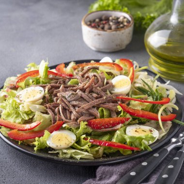 Çatal ve bıçakla servis edilen taze sebzeli sığır dili salatası.