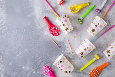 Gri arkaplandaki doğum günü partisinin üst görüntüsü: kağıt bardaklar, şekerler ve balonlar. Boşluğu kopyala