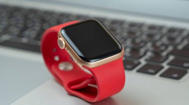 Minsk, Belarus - 07 Nisan 2021: Laptop klavyesinde kırmızı kayışlı Apple Watch. Pankart