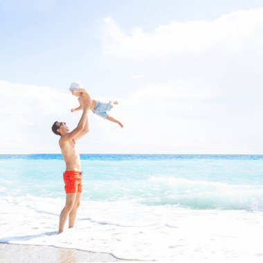 Baba güneşli bir günde denizde bir çocuğu havaya fırlatır. Yaz aile tatili.