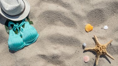 Yaz sahili arkaplanı ve yazı çerçevesi. Şapka, mayo, deniz yıldızı ve deniz kabukları. Üst görünüm