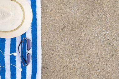 Havlu, şapka, kulaklık ve kumdaki güneş gözlüğü. Üst görünüm, alanı kopyala