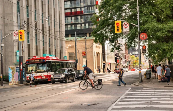 TORONTO, CANADA - 06 05 2021: Toronto şehir merkezindeki University Avenue kavşağında trafik ön planda bir bisikletçi ve arka planda TTC HybridElectric otobüsü