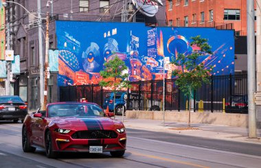 TORONTO, CANADA - 06 05 2021: Kırmızı Ford Mustang üstü açık spor araba Queen Caddesi boyunca ilerleyen 275 Queen Caddesi batı binasının duvarındaki duvar resmi