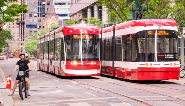 TORONTO, CANADA - 06 05 2021: Yeni Bombacı yapımı TTC tramvaylar yolu Toronto şehir merkezindeki King Caddesi 'ndeki bisikletçilerle paylaşıyor. Toronto Ulaşım Komisyonu bir toplu taşıma kurumudur.
