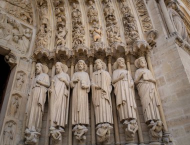 Paris, Fransa 08 04 2023: Fransa 'nın Paris kentindeki Notre Dame Katedrali' nin batı cephesindeki diğer azizlerle birlikte Aziz Denis 'in başını taşıdığı gotik taş oyma ve heykellerin yakın çekimi.