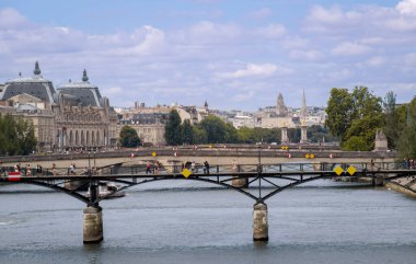 Paris, Fransa - 08 04 2023: Paris şehir merkezindeki Seine nehir kıyılarının geniş bir manzarası. Görüntü, ön planda Orsay Müzesi ve arka planda klasik Haussmann binaları bulunan ikonik Pont des Arts yaya köprüsünü gösteriyor. Bu...