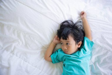 Yataktaki mutlu çocuğun otantik yakın çekimi. Yeni nesil kavramı, aile, ebeveynlik, özgünlük, evlat.