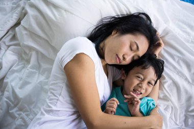 Mutlu anne ve oğlunun bir yatakta otantik yakın çekimi. Yeni nesil kavramı, aile, ebeveynlik, özgünlük, bağlantı