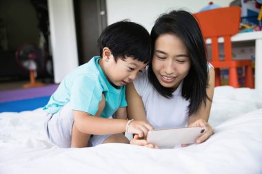 Mutlu anne ve oğlunun fotoğraf çekerken, selfie çekerken, video görüşmesi yaparken ya da bir yatakta akrabalarını çekerken. Yeni nesil kavramı, aile, ebeveynlik, özgünlük, bağlantı