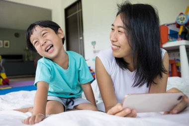 Mutlu anne ve oğlunun fotoğraf çekerken, selfie çekerken, video görüşmesi yaparken ya da bir yatakta akrabalarını çekerken. Yeni nesil kavramı, aile, ebeveynlik, özgünlük, bağlantı