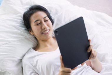 Evdeki yatakta dijital tablet kullanan bir kadın. Yeni nesil, aile, ebeveynlik, gerçeklik, bağlantı, teknoloji kavramının kullanımı