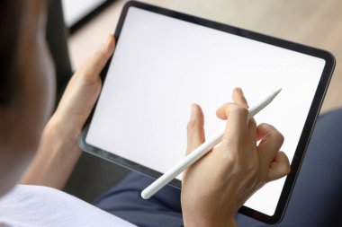 Oturma odasındaki kanepede dijital tablet beyaz ekranlı el çizimi yapan kadın. Teknoloji kavramı, bağlantı, iletişim.