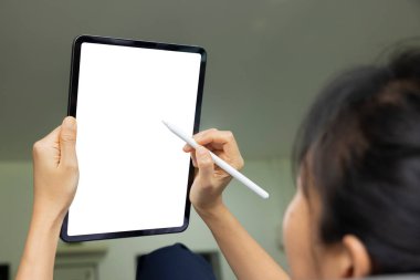 Oturma odasındaki kanepede dijital tablet beyaz ekranlı el çizimi yapan kadın. Teknoloji kavramı, bağlantı, iletişim.