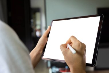 Oturma odasındaki kanepede dijital tablet beyaz ekranlı el çizimi yapan kadın. Teknoloji kavramı, bağlantı, iletişim.