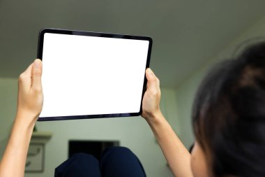 Oturma odasındaki kanepede dijital tablet beyaz ekranlı el kamerası olan kadın. Teknoloji kavramı, bağlantı, iletişim.