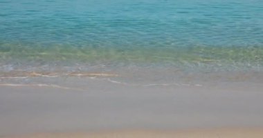 Mavi gökyüzüne karşı mavi denizi olan yumuşak bir sahil. Naithon Sahili, Phuket, Tayland 'da kıyıya vuran beyaz dalgalarla. Doğa, seyahat, gerçek, özgürlük kavramları. video 4K.