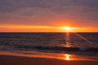 Günbatımı manzarasının portakal ışığına yansıyan deniz manzarası ve mavi su ferahlatıcı. Bang Tao Sahili, Phuket Eyaleti, Tayland. Seyahat kavramı, doğa. Kimse yok..