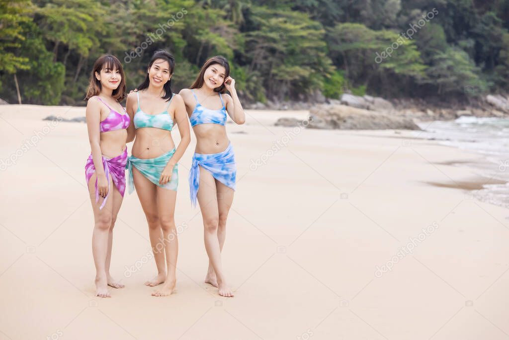 Three young women friends happily wear this bikini on a beach in Nai Thon Beach, Phuket Province, Thailand. Portrait of happy young woman smiling at sea. Concept about Travel, happiness, nature.