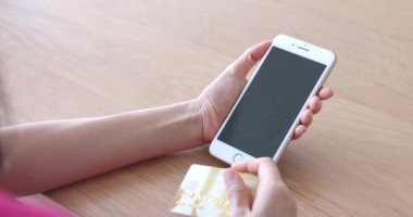 Yakın görüş, kredi kartı tutan kadın eller ve çevrimiçi banka ödemesi yapmak için akıllı telefon. Ödeme konsepti, alışveriş. 4k.