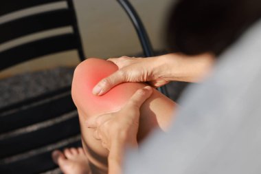 Kadının eli kırmızı iltihaplı ve morarmış yaralı diziyle yakın plan çekilmiş. Tıbbi konsept eklem ağrısı, eklem iltihabı, kemik hasarı, kas ağrısı ya da açık hava güneş ışığı arka planında burkulma..