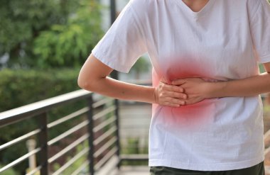 Kırmızı röfle ile karnını tutan bir kadın. Karın ağrısı, karaciğer hastalığı, böbrek ağrısı, apandisit ve sağlık ve tıbbi tedavi için mide ağrısı konsepti.