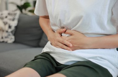 Kırmızı röfle ile karnını tutan bir kadın. Karın ağrısı, karaciğer hastalığı, böbrek ağrısı, apandisit ve sağlık ve tıbbi tedavi için mide ağrısı konsepti.