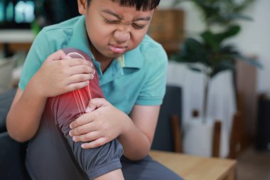 Diz eklem ağrısı çeken küçük bir çocuk, kırmızı x-ray kemik örtüsü, bacağa dokunan çocuk yaralanma, büyüme sancıları, iltihap ya da evde oynarken kaza geçiriyor..