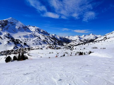Mavi gökyüzü ve uçak izleri olan Obertauern kayak bölgesi.