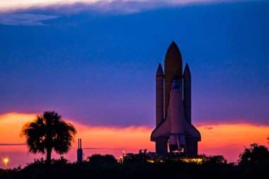 Space shuttle Discovery is silhouetted against the dawn sky as it rolls out to Launch Pad 39A at NASA& Kennedy Space Center in Florida.background template , elements of this image furnished by nasa clipart