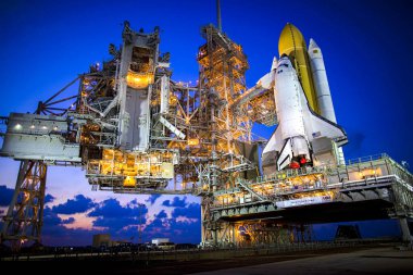 Uzay mekiği Discovery NASA 'nın arka plan şablonu üzerinde güneş batarken 39A fırlatma rampasında dimdik duruyor - NASA tarafından desteklenen bu görüntünün elementleri