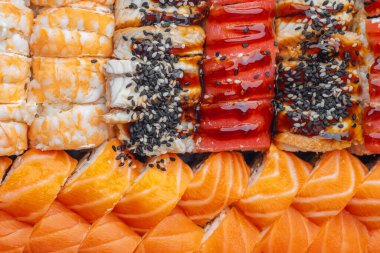 Suşi ruloları, somon balıklı karides ve siyah tabakta servis edilen yılan balıklı.