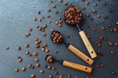 Koyu arkaplanda kaşık ölçmede kahve çekirdekleri