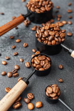 Kahve çekirdekleri gri arka plandaki kepçeleri ölçüyor