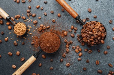 Ground Coffee ve gri arka planda kepçeli fasulyeler.