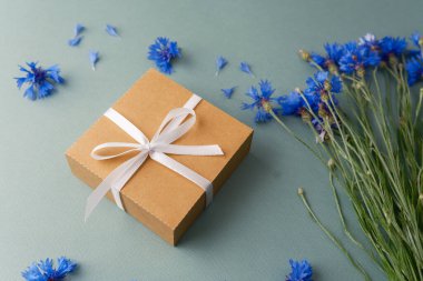 Yeşil arka planda hediye kutusu ve çiçek.