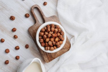 Tahta üzerinde sağlıklı fındık ve kremalı süt hazırlama tahtası ve beyaz bez.