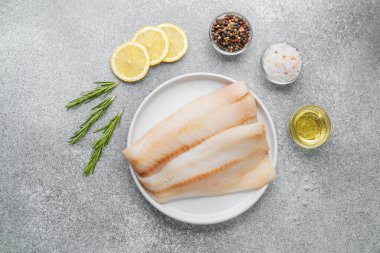 Gri arka planda baharat içeren ham pollock fileto.