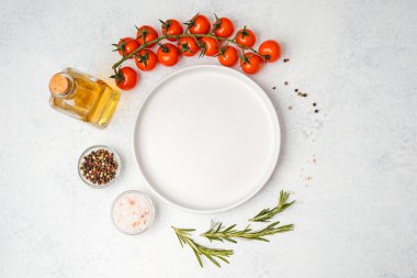 Domates, biberiye, tuz, yağ ve biber içeren yemek malzemelerinin bulunduğu boş beyaz tabağın üst görüntüsü