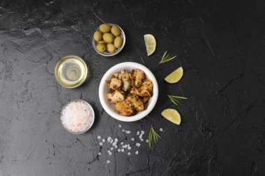 Sağlıklı öğle yemeği veya Akdeniz atıştırmalığı konsepti için biberiyeli deniz ürünleri salatası ve siyah zemin üzerine limon.