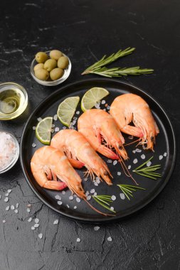 Biberiye, tuz ve zeytin ile servis edilen karides gurme aperatifler veya restoran menüsü konsepti için siyah tabakta