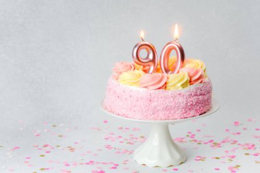 Krema gülleriyle süslenmiş hoş pembe pasta bir dönüm noktasını kutluyor..