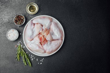 Baharatlı baharatlı tavuk kanatları ve koyu taşlı arka planda yağ.