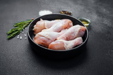 Siyah kasede çiğ tavuk budu ve baharat.