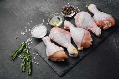 Siyah tahta üzerine yerleştirilmiş tavuk budu, otlar ve tuzlu.