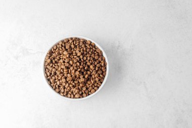 Beyaz desenli arka plana yerleştirilmiş bir kase kuru köpek maması.