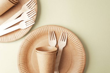 Yeşil arkaplan minimalist kavramında eko kağıt bardaklar ve çatallarla sürdürülebilir sofra takımı