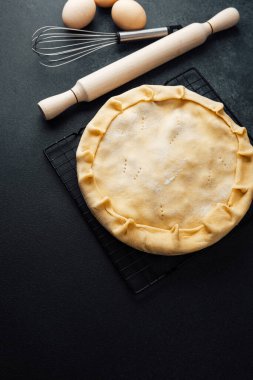 Ev yapımı turta kabuğu pişirme aletleriyle siyah tezgahta hazırlanıyor.