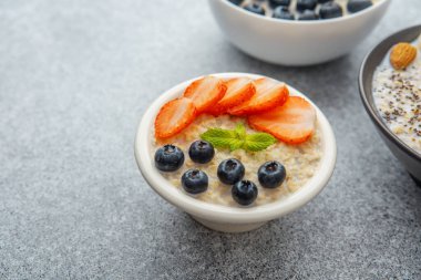 Yulaf ezmeli yulaf lapası, çilekli yaban mersini ve naneli beyaz kâse.