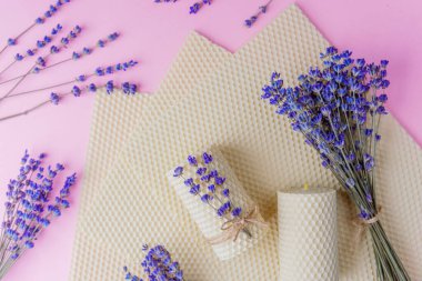 Balmumu mumlar ve pembe arka planda lavanta demetleri